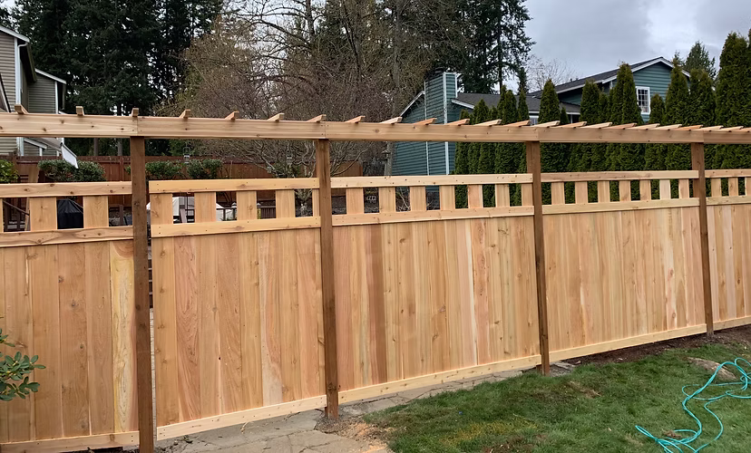A newly built wooden privacy fence with a decorative lattice top in a suburban backyard.